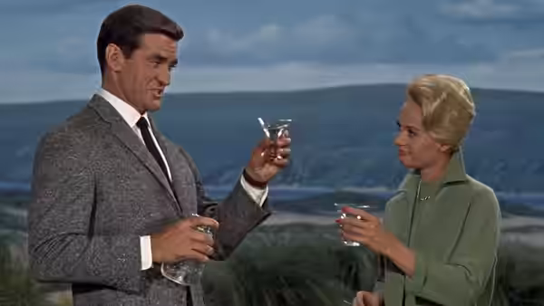 Mitch Brenner (Rod Taylor) and Melanie Daniels (Tippi Hedren) raise drinks by the coast