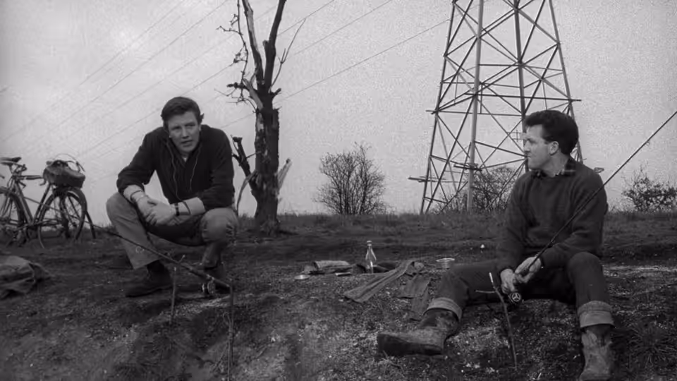 Arthur Seaton and a friend sit beside railway tracks beneath power lines
