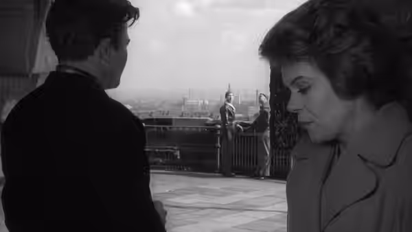 Arthur Seaton and Doreen stand on a rooftop terrace overlooking the city
