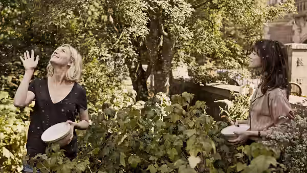 Justine (Kirsten Dunst) and Claire (Charlotte Gainsbourg) in a garden with falling petals