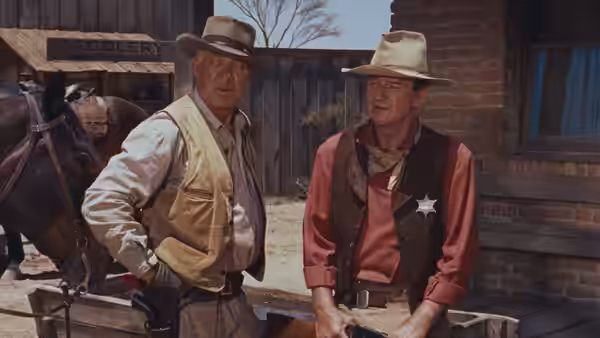 Sheriff Chance (John Wayne) standing with another cowboy outdoors