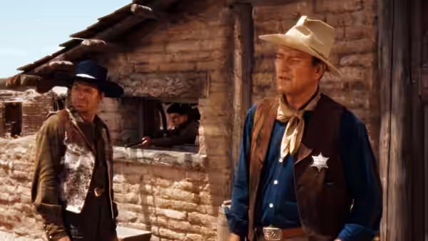 Sheriff Chance (John Wayne) outside a wooden building with another man