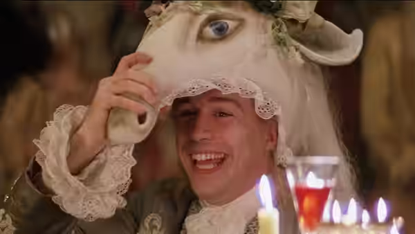 Mozart (Tom Hulce) smiling beneath a goat mask at a candlelit party