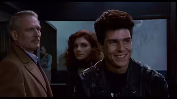 Vincent Lauria (Tom Cruise), Carmen (Mary Elizabeth Mastrantonio), and Eddie Felson (Paul Newman) stand together indoors