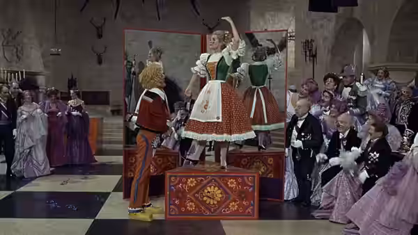 Performers in bright costumes dancing on a raised stage before spectators