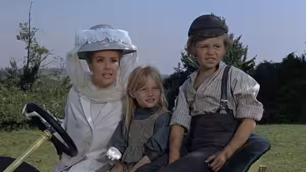 Woman in white hat sitting outdoors with two children on her lap