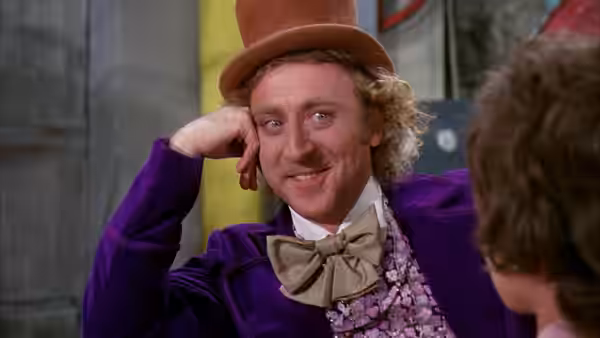 Willy Wonka (Gene Wilder) smiles with hand resting on his head