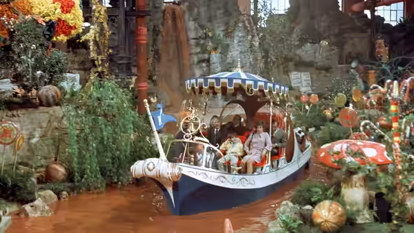 Willy Wonka and guests ride a boat on the chocolate river