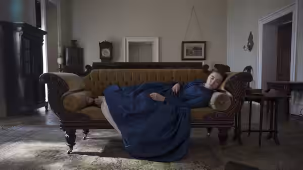 Katherine Lester (Florence Pugh) lies across a sofa in a furnished sitting room