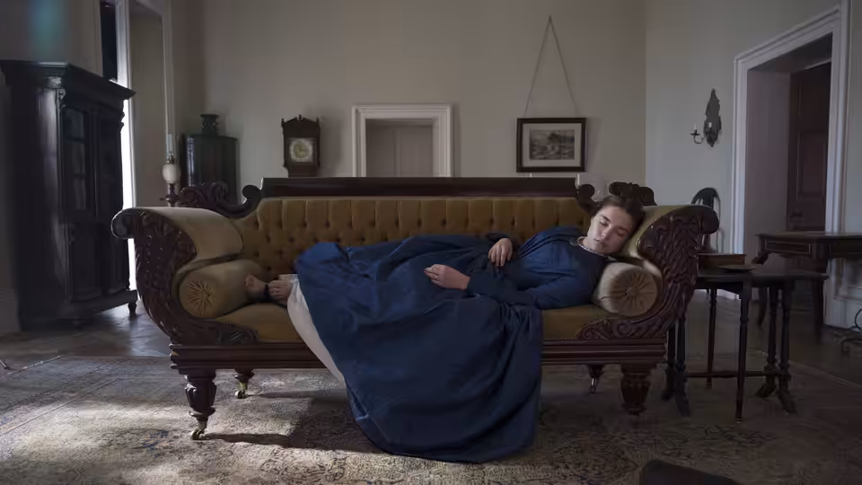 Katherine Lester (Florence Pugh) lies across a sofa in a furnished sitting room