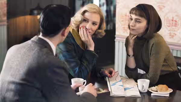 Carol Aird (Cate Blanchett) and Therese Belivet (Rooney Mara) seated with a man at a diner table