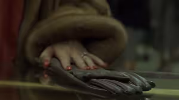 A woman's hand with red nail polish resting on leather gloves