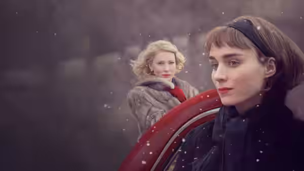 Carol Aird (Cate Blanchett) and Therese Belivet (Rooney Mara) standing beside a red car in the snow