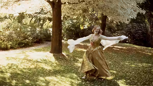 Juliet (Kate Winslet) dancing with arms outstretched in a sunlit garden