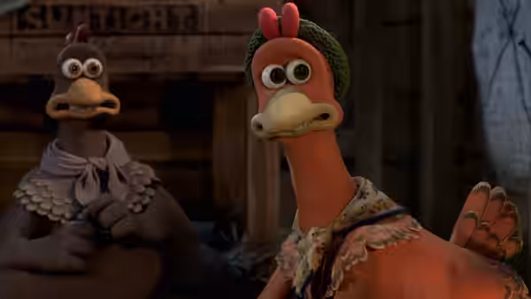 Two chickens standing side by side in a dimly lit wooden interior