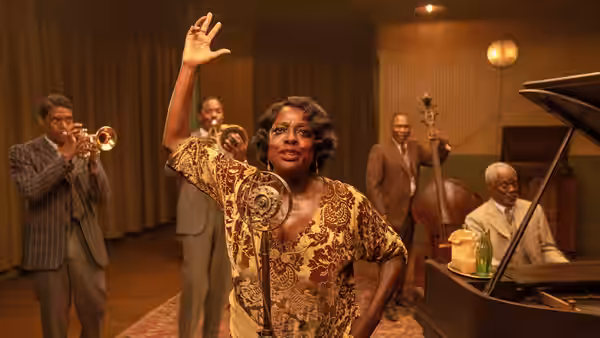 Ma Rainey (Viola Davis) raises her hand beside the band in the recording studio