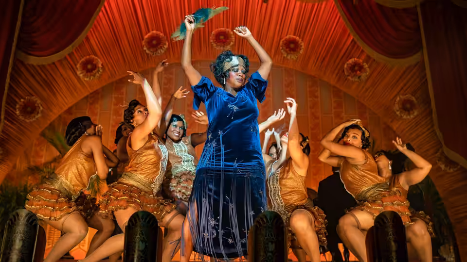 Ma Rainey (Viola Davis) raises a feathered fan as dancers move around her onstage