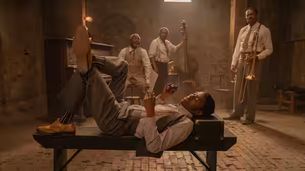 Levee (Chadwick Boseman) reclines on a table while bandmates gather in the rehearsal room