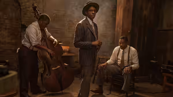 Levee (Chadwick Boseman) stands between bandmates with a double bass in the rehearsal room