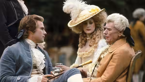 Three figures in 18th century finery sit together at an outdoor gathering