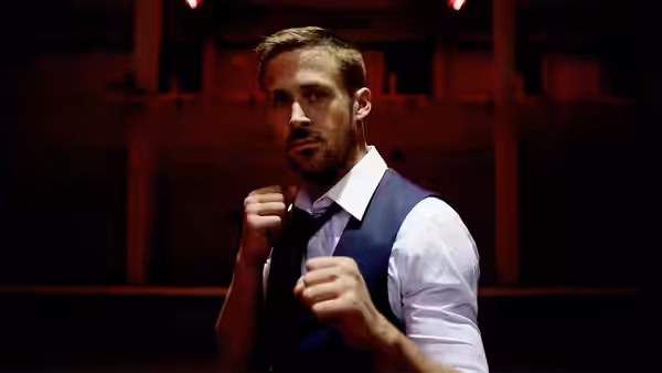 Julian (Ryan Gosling) raises his fists in a fighting stance inside a red-lit room