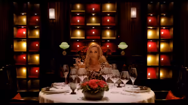 Crystal (Kristin Scott Thomas) sits at a lavishly set restaurant table
