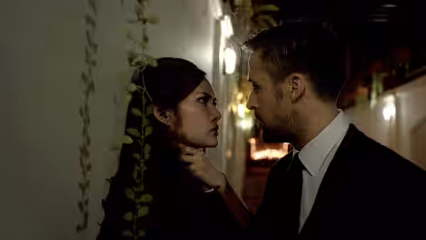 Julian (Ryan Gosling) holds Mai’s chin as they face each other indoors
