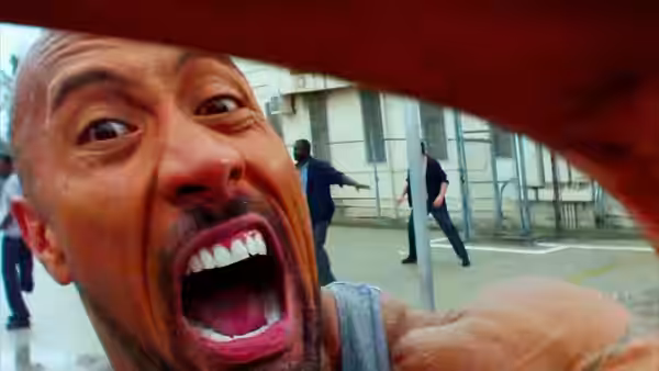 Paul Doyle (Dwayne Johnson) screams close to the camera as men run behind him