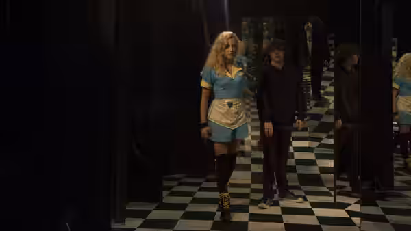 Anna Peterson (Maika Monroe) and Luke Peterson (Brendan Meyer) walk through a mirrored, checkered hallway