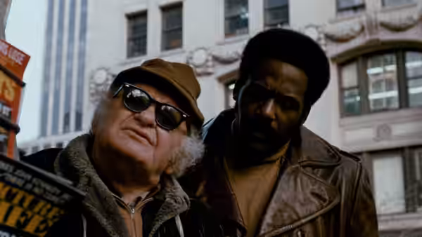 John Shaft (Richard Roundtree) stands beside an older man wearing sunglasses on a city sidewalk