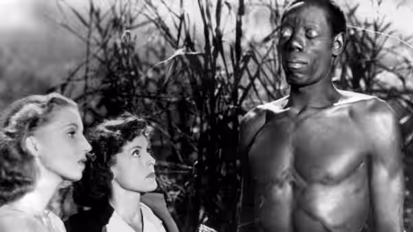 Carrefour (Darby Jones) stands among two women, his eyes turned upward