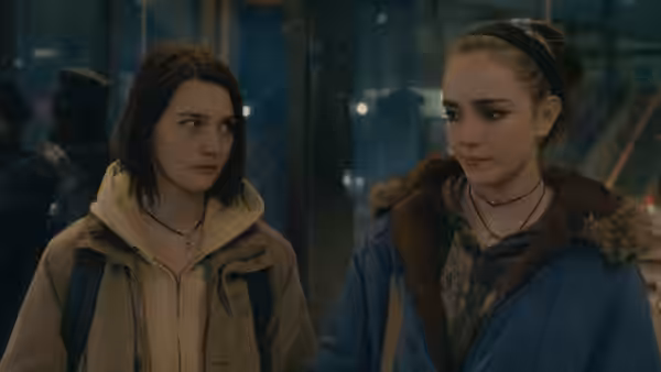 Autumn (Sidney Flanigan) and Skylar (Talia Ryder) walk together through a dim station