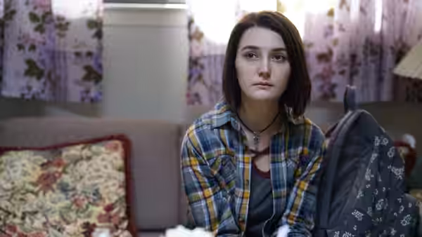 Autumn (Sidney Flanigan) sits quietly on a sofa in a living room