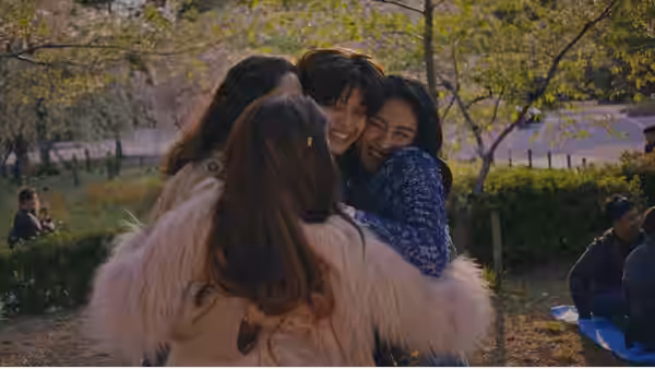 Women embracing in a group hug outdoors under blooming trees