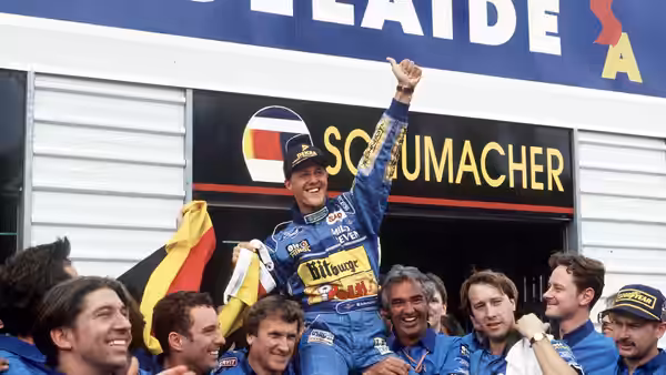 Michael Schumacher raising his fist while carried by his team