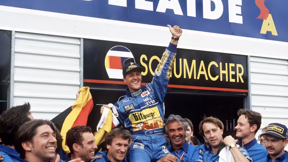 Michael Schumacher raising his fist while carried by his team