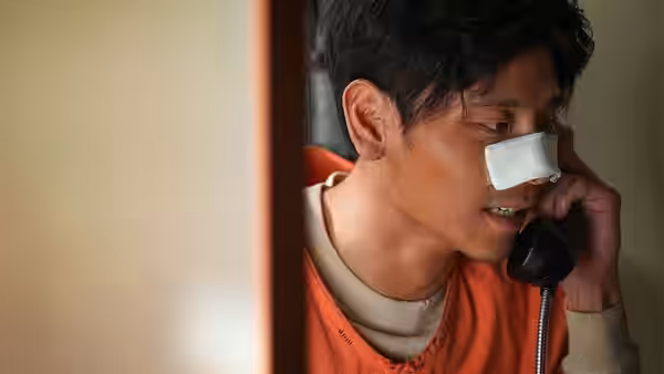 Injured man with nose bandage talks on a telephone in a doorway