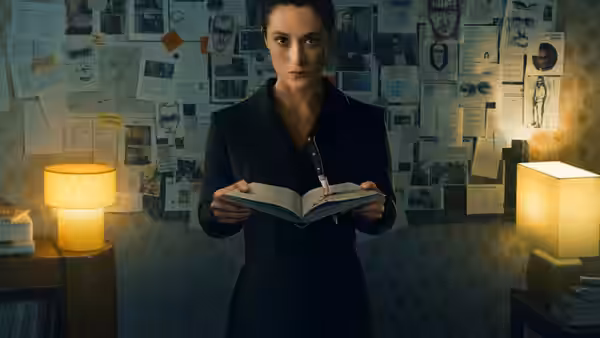 Lisa Konrad (Friederike Becht) holding an open book in a room lined with papers