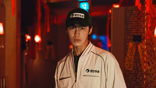 Young man in white jacket and cap standing amid red lanterns at night