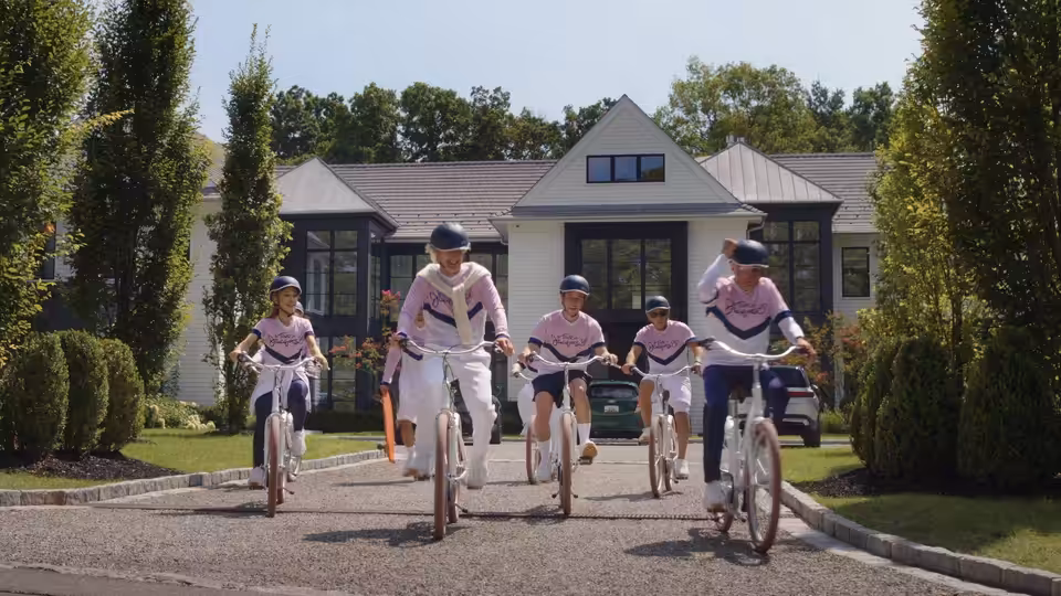 Four cyclists in matching outfits riding down a suburban driveway