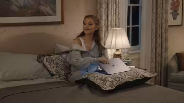 Olivia Jones (Ariana Grande) sitting on a bed with an open laptop