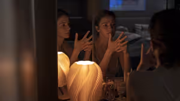 A woman gesturing at her reflection in a mirror