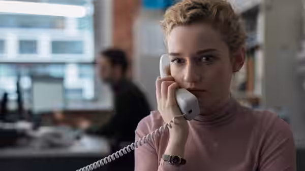 Jane (Julia Garner) speaks on a corded office phone while seated at her desk
