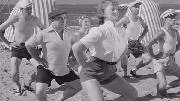 Holidaymakers follow a woman leading calisthenics on the beach