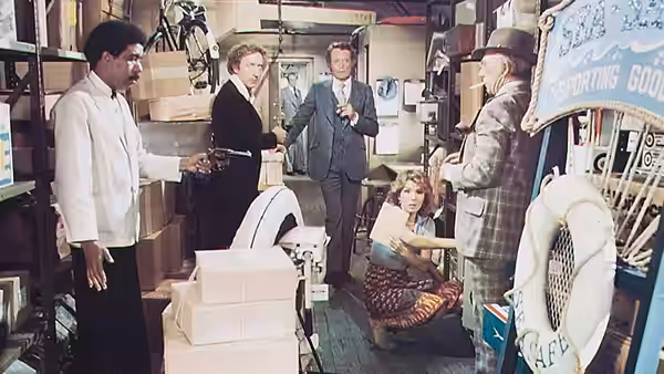 George Caldwell and Hilly Burns meet several men in a cluttered shop
