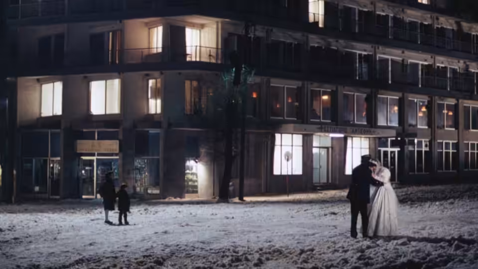 A couple embraces in a snowy street while two children stand nearby