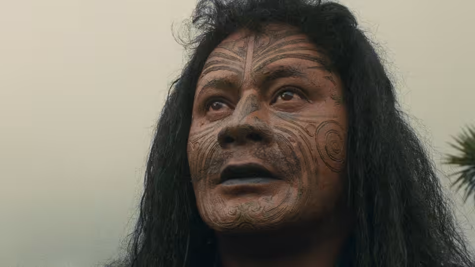 Te Wheke (Anzac Wallace) looks upward, his face marked with tā moko