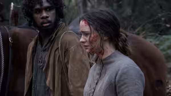 Billy (Baykali Ganambarr) looks toward bloodied Clare as they stand beside a horse