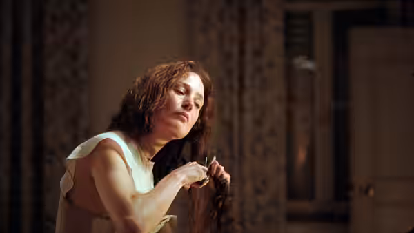 Empress Elisabeth (Vicky Krieps) braids her hair in a dimly lit room