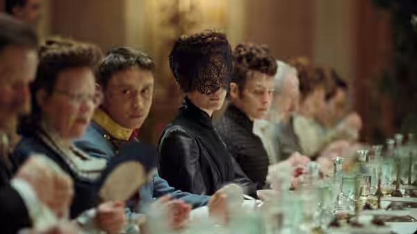 Empress Elisabeth (Vicky Krieps) sits veiled at a formal dining table among guests